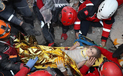 Rescue workers, who were trying to find survivors of an earthquake, surround Ayda Gezgin after they pulled the young girl out alive from the rubble of a collapsed apartment in the Turkish coastal city of Izmir, November 3, 2020, (AFAD via AP)