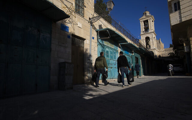 Palestinians walk past closed stores near the Church of the Nativity in the West Bank City of Bethlehem, Monday, November 23, 2020. (AP Photo/Majdi Mohammed)