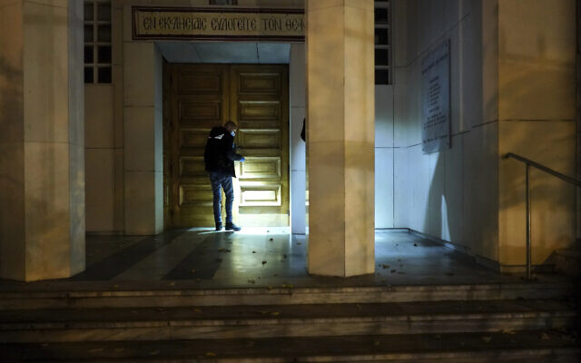 A police officer searches for clues after a priest was shot, Oct. 31, 2020, in the city of Lyon, central France (AP Photo/Laurent Cipriani)