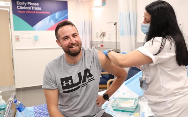 Sheba Medical Center nurse Hala Litwin injects a dose into Israel's first human test subject, Segev Harel, as part of trials for Israel's experimental coronavirus vaccine, BriLife, on November 1, 2020. (Defense Ministry)