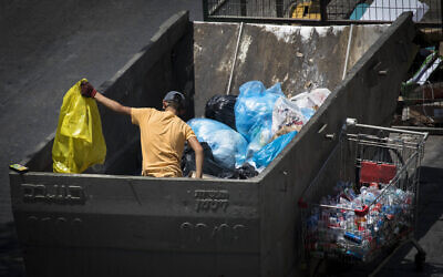 A teenager search for cans through a garbage container in the center of Jerusalem on July 13,2020 (Olivier Fitoussi/Flash90)