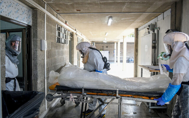 Illustrative: Workers prepare a body before a funeral ceremony at a morgue for coronavirus victims, in Holon, on October 28, 2020. (Flash90)