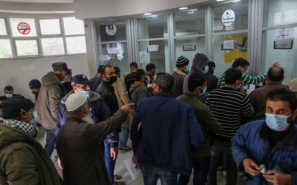 Palestinians receive their $100 financial aid as part of the aid allocated by Qatar to poor families, through a post office, in the town of Khan Yunis, southern Gaza Strip, on December 3, 2020. (Abed Rahim Khatib/Flash90)