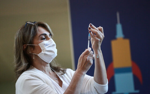An Israeli medical worker holds a coronavirus vaccination, at Tel Aviv Sourasky Medical Center on December 20, 2020 (Miriam Alster/Flash90)