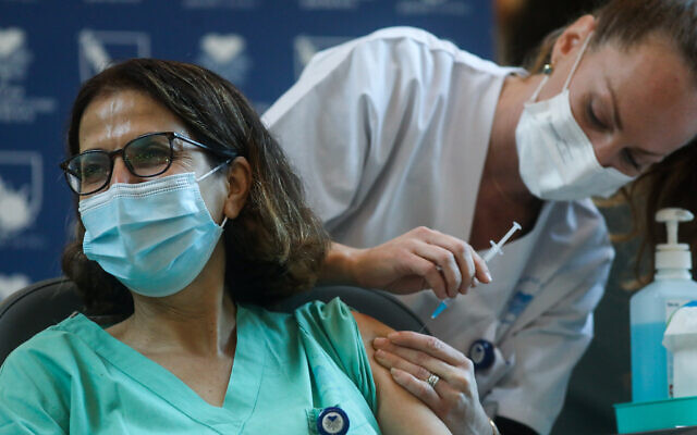 An Israeli medical worker receives a COVID-19 vaccine, at Tel Aviv Sourasky Medical Center on December 20, 2020 (Miriam Alster/Flash90)