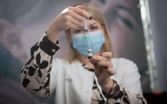 A Clalit healthcare worker prepares a COVID-19 vaccine at a vaccination center in Tel Aviv on December 22, 2020. (Miriam Alster/Flash90)