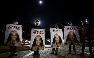 Demonstrators holds placards showing Ahuvia Sandak as they protest against his death in a car crash during a police chase last week, at Rabin Square in Tel Aviv on December 29, 2020. (Miriam Alster/Flash90)
