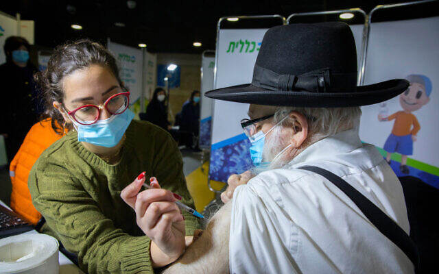 An ultra-Orthodox man receives a Covid-19 vaccine, at a Kupat Holim Clalit vaccination center in Jerusalem, on December 29, 2020. (Olivier Fitoussi/Flash90)