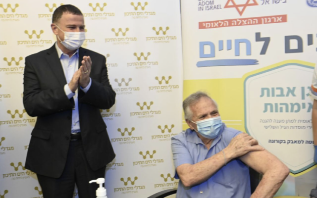 Health Minister Yuli Edelstein applauds as a man is vaccinated at an eldercare facility in Sha'arei Tikva, December 22, 2020 (Health Ministry)