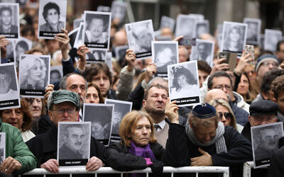 Mourners hold up pictures of people who died in the bombing of the AMIA Jewish center that killed 85 people on the 25th anniversary of the attack in Buenos Aires, Argentina, July 18, 2019. (AP/Natacha Pisarenko)