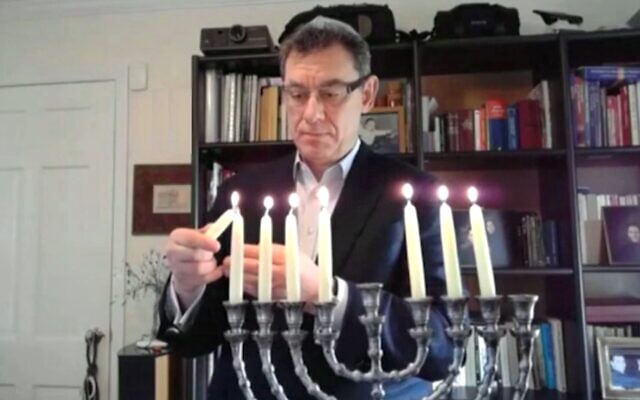 Pfizer CEO Albert Bourla lights the Hanukkah candles at a virtual ceremony organized by the Isaeli embassy in Washington, on December 16, 2020. (Screen capture/Israeli Embassy in DC)