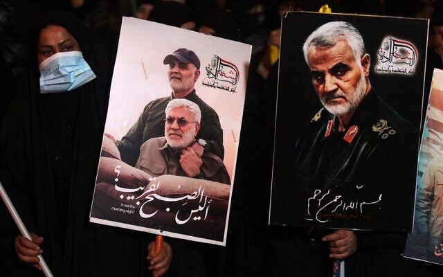 People carry portraits of late Iraqi commander Abu Mahdi al-Muhandis and Iranian commander Qasem Soleimani at Baghdad Airport, in Baghdad on January 2, 2021, at the site of their killing (AHMAD AL-RUBAYE / AFP)