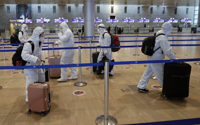 Passengers wearing full protective suits and masks to protect against the COVID-19 pandemic push their luggage at the departures area at Ben Gurion Airport on January 19, 2021. (Jack Guez/AFP)