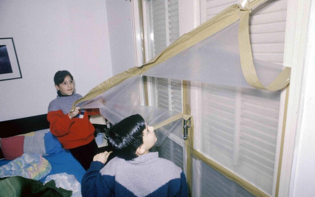 Israeli children pull down protective plastic sheeting from windows that was meant to protect them from chemical weapons in a Scud missile attack during the 1991 First Gulf War. (Michael Tzarfati/Defense Ministry Archive)