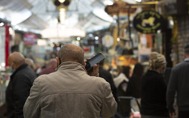 A man speaks on his mobile phone at the Mahane Yehuda market in Jerusalem, December 23, 2020. (Maya Alleruzzo/AP)