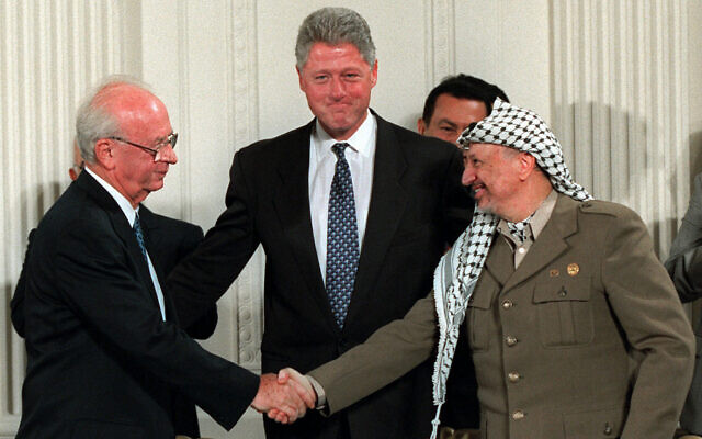 Then US President Bill Clinton, center, looks on as Israeli Prime Minister Yitzhak Rabin, left, and PLO leader Yasser Arafat shake hands in the East Room of the White House after signing the Middle East accord in Washington on September 28, 1995. (AP Photo/Doug Mills, File)