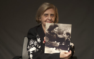 Illustrative: Tova Friedman, an 82-year-old Polish-born Holocaust survivor, holds a photograph of herself as a child with her mother, who also survived the Nazi death camp Auschwitz, in New York, December 13, 2019. (World Jewish Congress via AP)