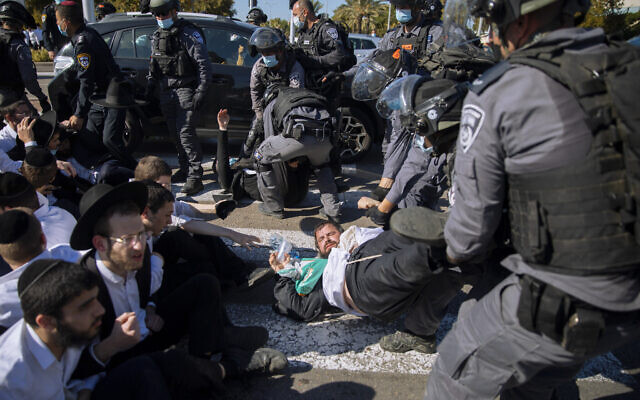 Israeli police officers clash with ultra-Orthodox Jews during a protest over the coronavirus lockdown restrictions, in Ashdod, Israel, January 24, 2021. (AP/Oded Balilty)