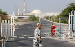 In this August 20, 2010, photo, an Iranian security guard walks past a gate of the Bushehr nuclear power plant as its reactor building is seen in background, just outside the city of Bushehr 750 miles (1,245 kilometers) south of the capital Tehran, Iran. (AP Photo/Vahid Salemi)