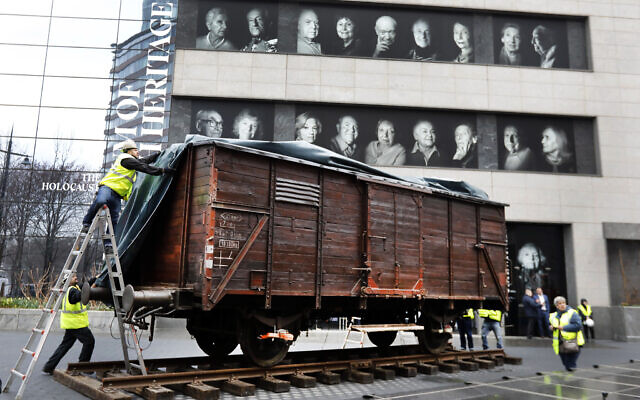 Illustrative: Portraits of Holocaust survivors are displayed at the Museum of Jewish Heritage as a vintage German train car, like those used to transport people to Auschwitz and other death camps, is uncovered on tracks outside the museum, in New York, Sunday, March 31, 2019.  (AP Photo/Richard Drew)