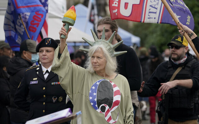 A person dressed as Lady Liberty wears a shirt with the letter Q, referring to QAnon, as protesters take part in a protest, Wednesday, Jan. 6, 2021, at the Capitol in Olympia, Wash., against the counting of electoral votes in Washington, DC, affirming President-elect Joe Biden's victory. (AP Photo/Ted S. Warren)