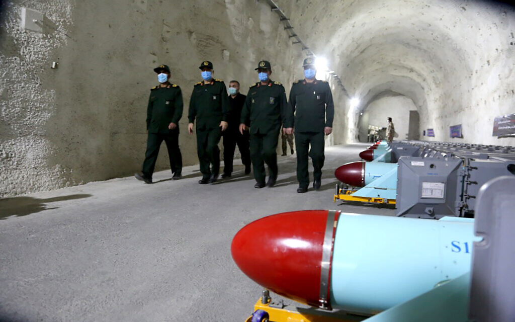 In this photo released Jan. 8, 2021, commanders of Iran's paramilitary Islamic Revolutionary Guard Corps walk past missiles during a visit to a new military base in an undisclosed location. (Sepahnews via AP)