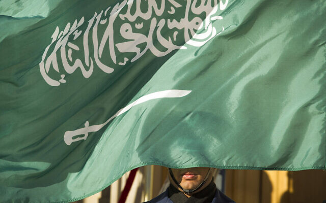 An honor guard member is covered by the flag of Saudi Arabia, in Washington, on March 22, 2018. (AP Photo/Cliff Owen, File)