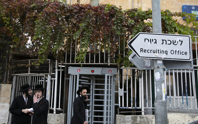 Ultra-Orthodox men walk outside the IDF recruitment office in Jerusalem, on December 5, 2019. (Olivier Fitoussi/Flash90)