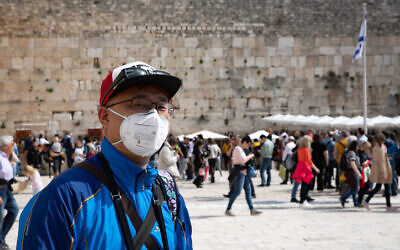 An American tourist wearing a face mask tours at the Western Wall in the Old City of Jerusalem on February 27, 2020 (Olivier Fitoussi/Flash90)
