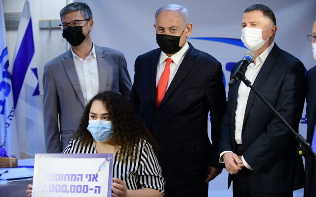 Prime Minister Benjamin Netanyahu (C) and Health Minister Yuli Edelstein (R) at a Maccabi Healthcare Services clinic in the central city of Ramle, as a kindergarten teacher becomes the 2 millionth Israeli to be vaccinated against COVID-19, January 14, 2021. (Tomer Neuberg/Flash90)