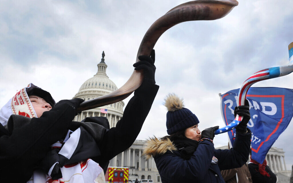 Two women, one wearing a tallit, blow the shofar amid the Capitol rioting, Jan. 6, 2021. (Lloyd Wolf via JTA)