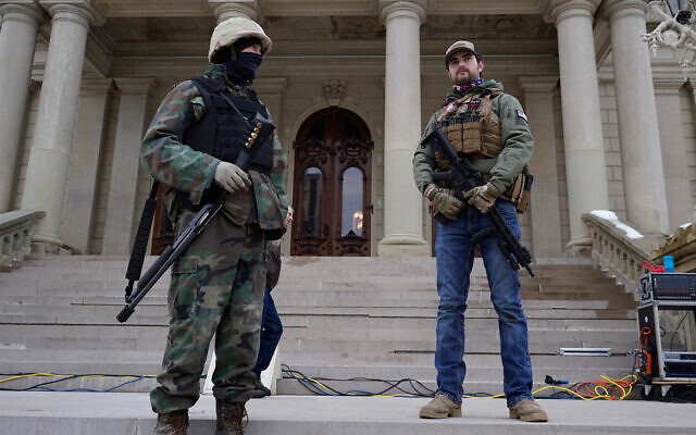 Armed civilians stand on the steps of the Michigan state capitol building after a rally in support of US President Donald Trump in Lansing, Michigan, January 6, 2021. (AP Photo/Paul Sancya)