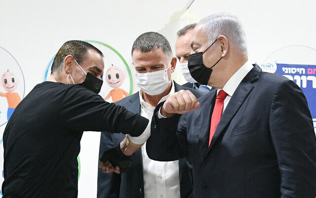 Prime Minister Benjamin Netanyahu, right, and Health Minister Yuli Edelstein, center with Muhammad Abd al-Wahhab Jabarin, the millionth Israeli to get a COVID-19 vaccine, and medical staff in Umm al-Fahm, January 1, 2021. (Haim Zach/GPO)