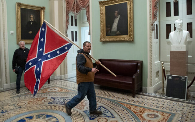 A supporter of US President Donald Trump carries a Confederate flag in the US Capitol Rotunda in Washington, DC, January 6, 2021. (Saul Loeb/AFP)