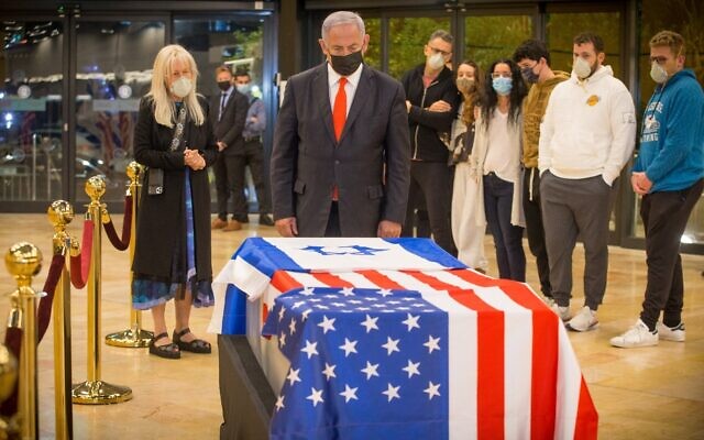 Prime Minister Benjamin Netanyahu pays his respects to the late Jewish-American billionaire Sheldon Adelson after his coffin arrived at Ben Gurion Airport, January 14, 2021. (Ami Shooman/Israel Hayom)