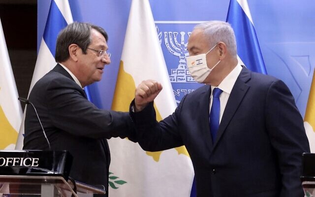 (L to R) Cyprus' President Nicos Anastasiades elbow-bumps Prime Minister Benjamin Netanyahu (mask-clad), during a joint press statement after their meeting at the Prime Minister's Office in Jerusalem on February 14, 2021. (Marc Israel SELLEM / POOL / AFP)