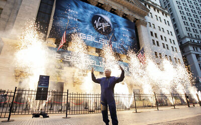 Sir Richard Branson, founder of Virgin Galactic, poses for a photo outside the New York Stock Exchange as fireworks are exploded before his company's IPO, performed via a reverse merger with a SPAC, on Monday, Oct. 28, 2019. (AP/Richard Drew)