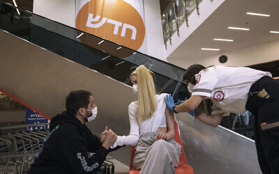 A paramedic from Magen David Adom medical services, administers a dose of the Pfizer-BioNtech COVID-19 vaccine to a woman at an Ikea store  in Rishon Lezion, Israel, Feb. 22, 2021 (AP Photo/Tsafrir Abayov)