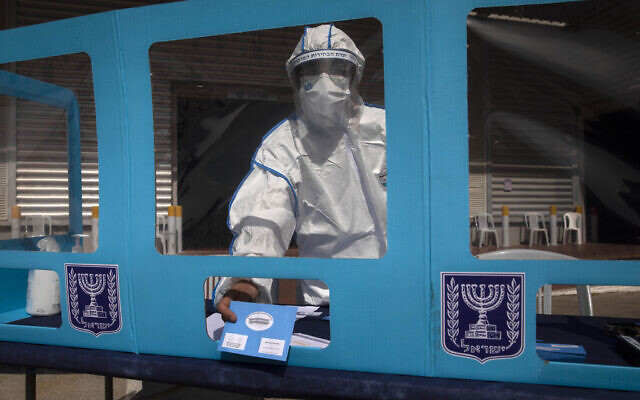 Israeli workers show a drive-by voting station during a media tour demonstration of coronavirus measures prior to upcoming elections, at the central elections logistics center in Shoham, Israel, February 23, 2021. (AP/Sebastian Scheiner)