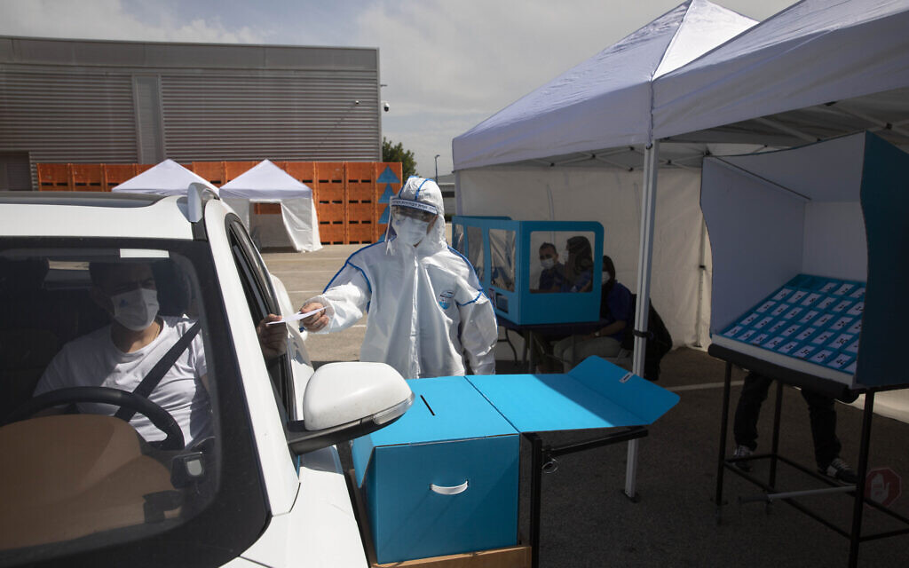 Workers show a drive-by voting station during a media tour demonstration of coronavirus measures prior to upcoming elections, at the central elections logistics center in Shoham, Israel, Tuesday, February 23, 2021. (AP/Sebastian Scheiner)