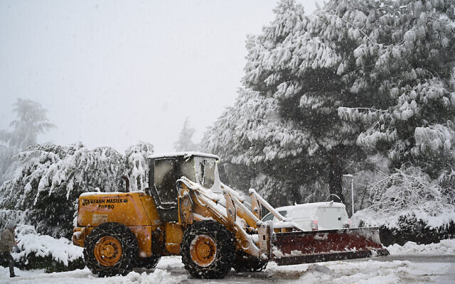 A tractor clears the snow off the ground in Kibbutz Marom Golan, in the Golan Heights February 17, 2021 (Michael Giladi/Flash90)