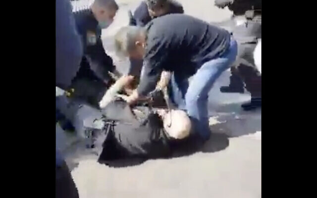 Police officers wrestle a shop owner in Holon to the ground to prevent him from stabbing himself, after he was fined for putting his merchandise on the sidewalk, February 24, 2021. (Screen capture: Twitter)