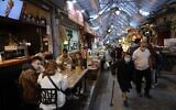 People eat at a restaurant in Jerusalem's main market after authorities reopened restaurants, bars and cafes to 'green pass' holders on March 11, 2021. (Emmanuel DUNAND / AFP)