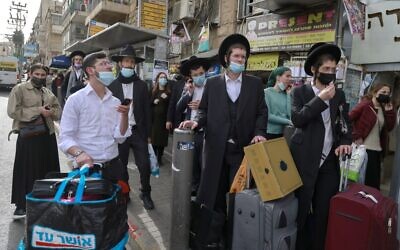 People wait at a bus stop in an ultra-Orthodox Jewish neighborhood in Jerusalem, on March 11, 2021 (MENAHEM KAHANA / AFP)
