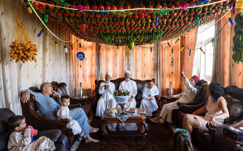 Samaritans sitting under their Sukkah decorated with fruits and vegetables during Sukkot holiday. Nablus, Palestinian territories, October 2017. (Yadid Levy)