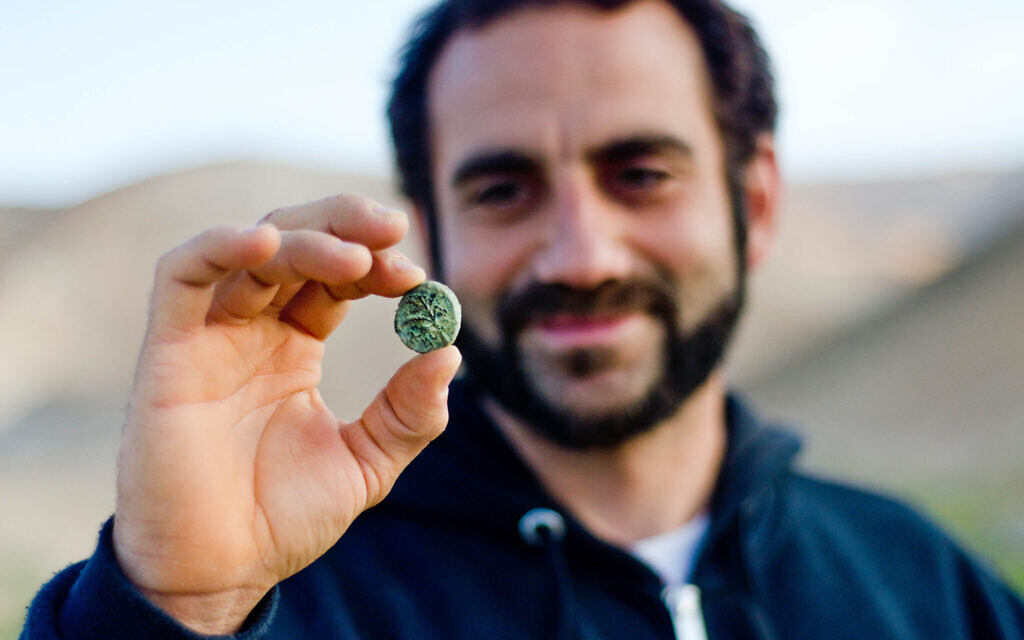 Archaeologist Hagay Hamer holding a Bar Kokhba coin found in the desert. (Yoli Schwartz, Israel Antiquities Authority)