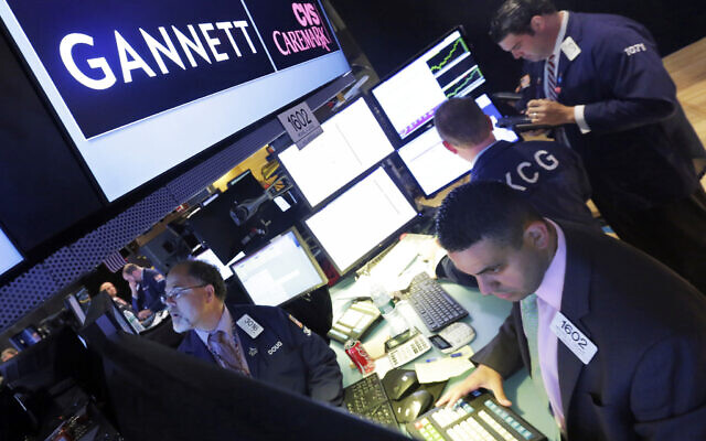 In this Aug. 5, 2014, file photo, specialist Michael Cacace, foreground right, works at the post that handles Gannett on the floor of the New York Stock Exchange. J(AP Photo/Richard Drew)