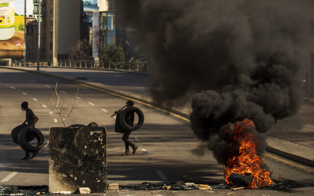 Protesters burn tires to close the main road, after the Lebanese pound hit a record low against the dollar on the black market, in Beirut, Lebanon on March 6, 2021. (AP/Hassan Ammar)