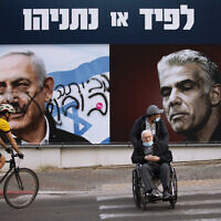 An election campaign billboard for the Likud party that shows a portrait of its leader Benjamin Netanyahu, left, and Yesh Atid head Yair Lapid in Ramat Gan, March 21, 2021. (AP Photo/Oded Balilty)