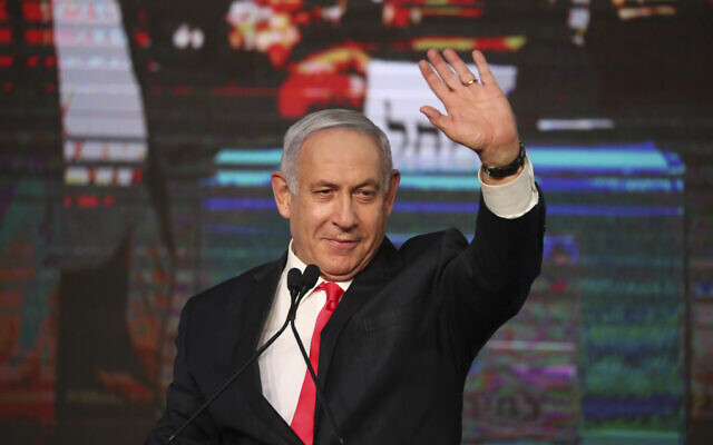 Prime Minister Benjamin Netanyahu waves to his supporters after the first exit poll results for Knesset elections at his Likud party’s headquarters in Jerusalem, March 24, 2021. (AP Photo/Ariel Schalit)